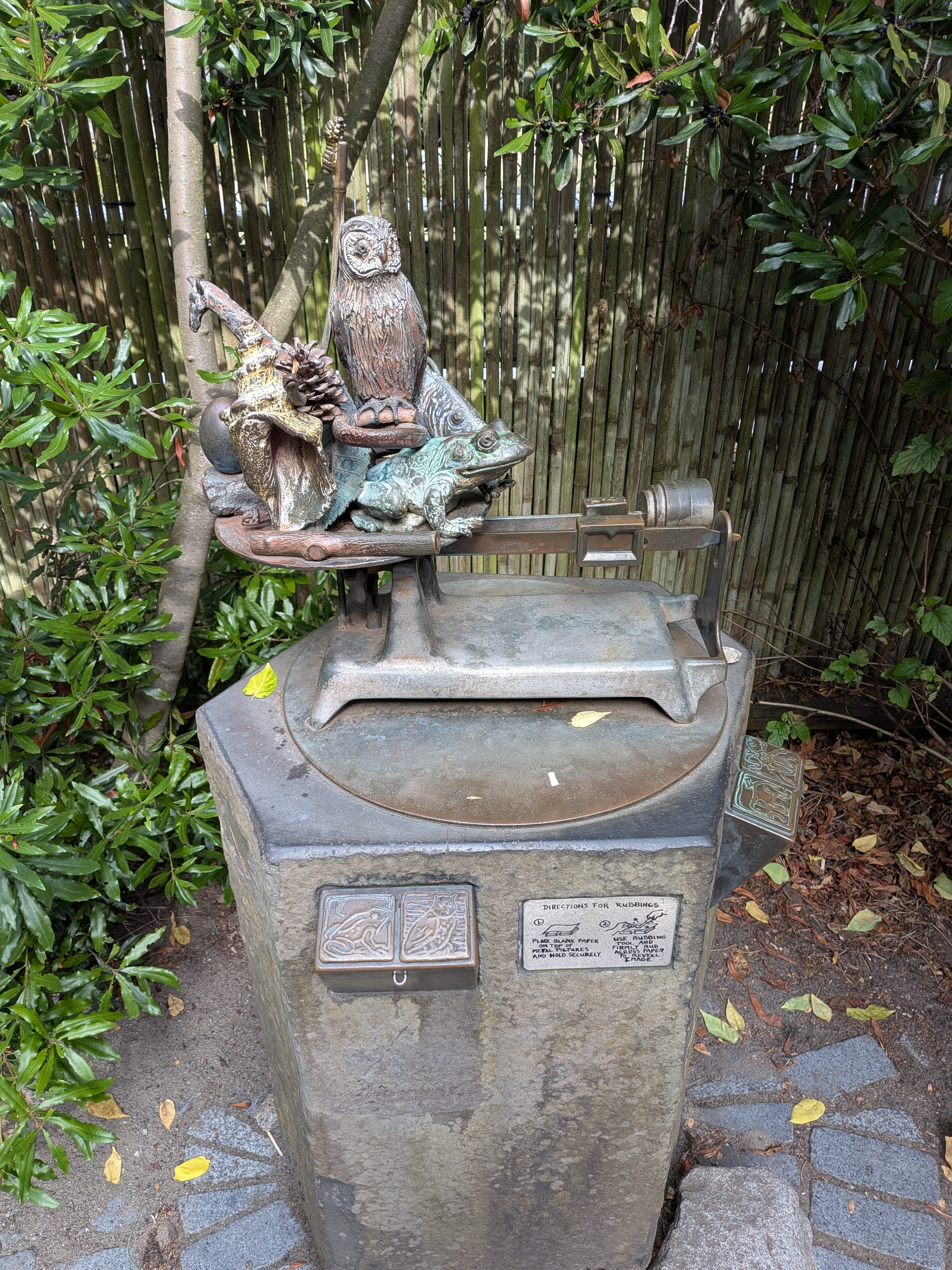 An image of a bronze statue that contains several animals sitting on the plate of a sliding scale. 